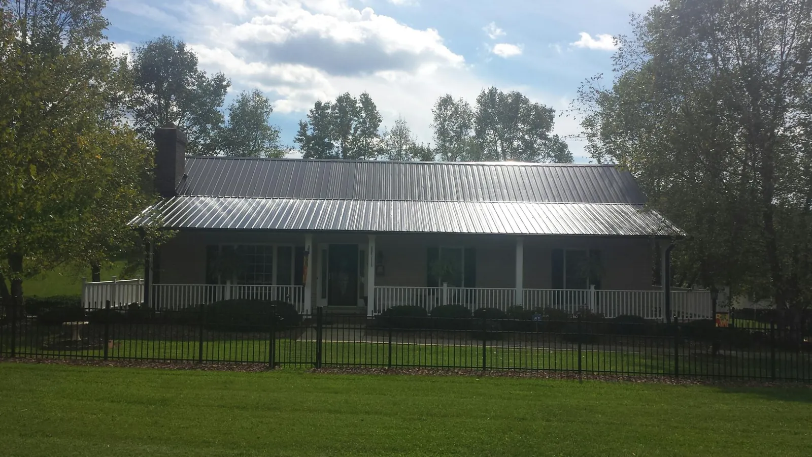 Gray metal roof on a brick ranch with a full width front porch — Gutter Guard Installation work by our crew in Estero